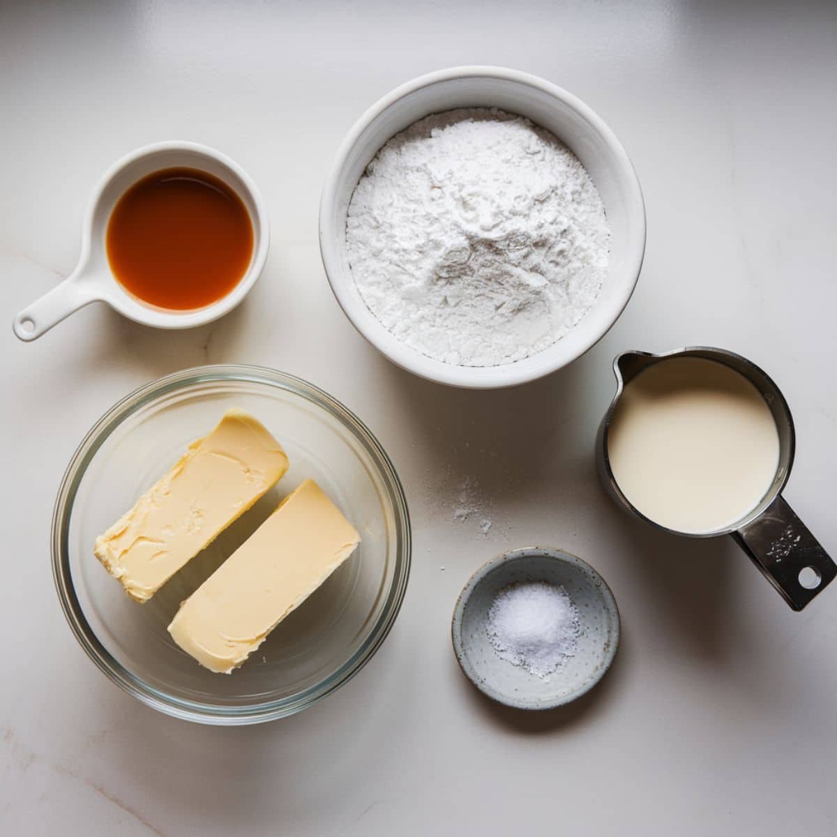 a bowl of flour and butter with a measuring cup of liquid and a spoon of butter
