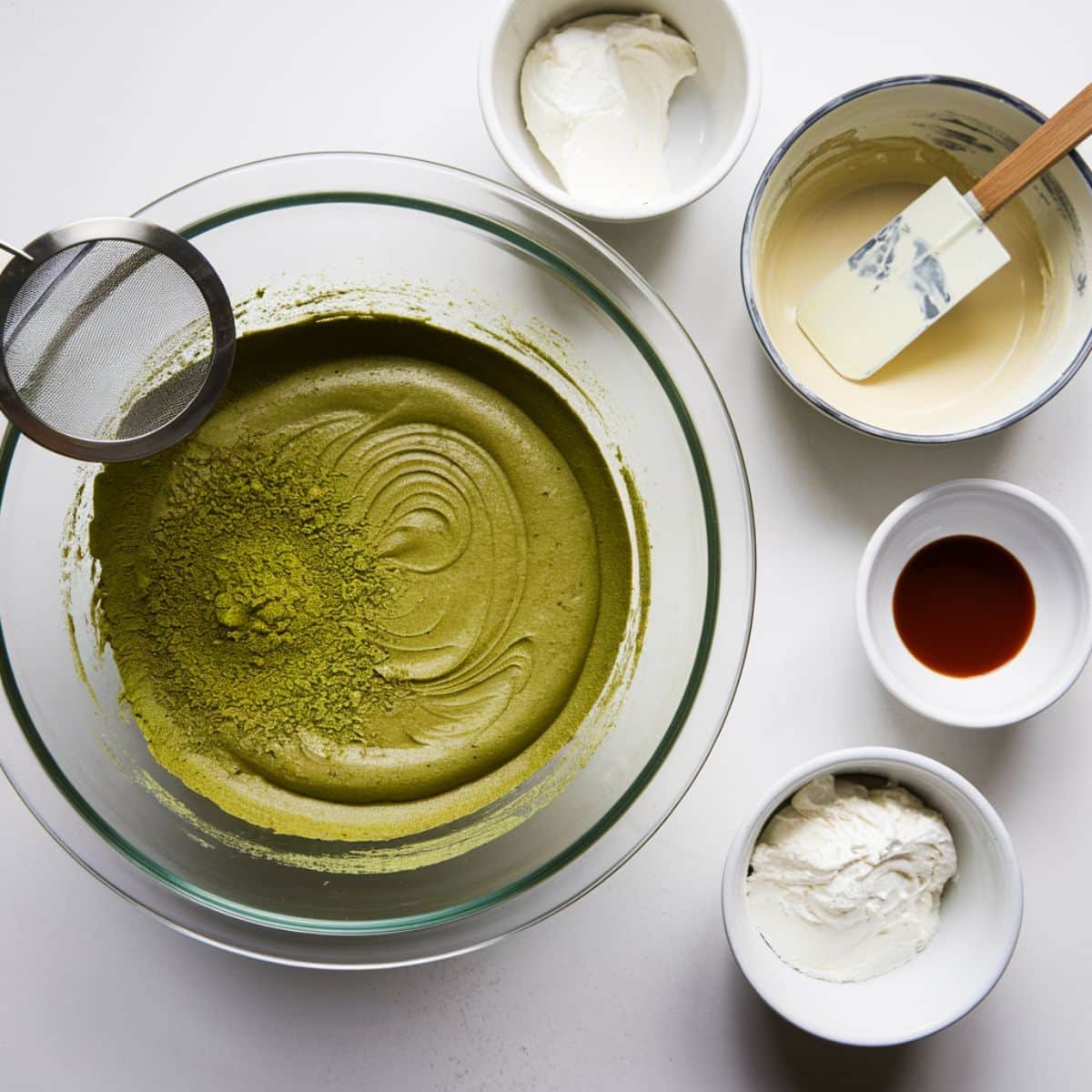 a bowl of green food with different bowls of cream and a sieve