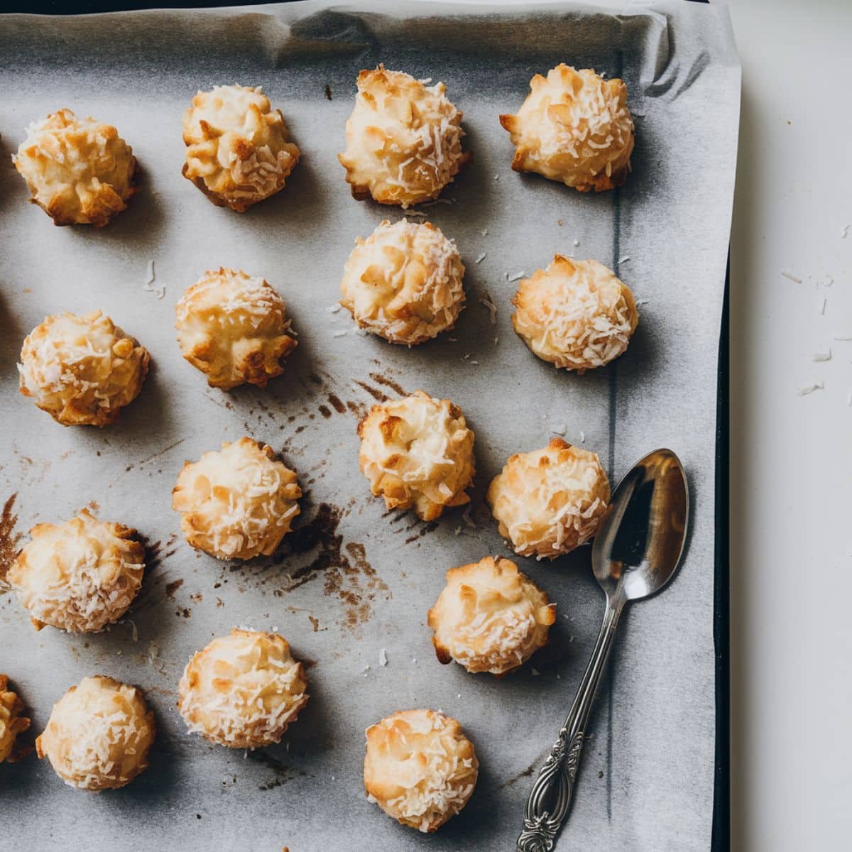 Scooped coconut macaroon mounds placed on a parchment-lined baking sheet, ready for the oven.