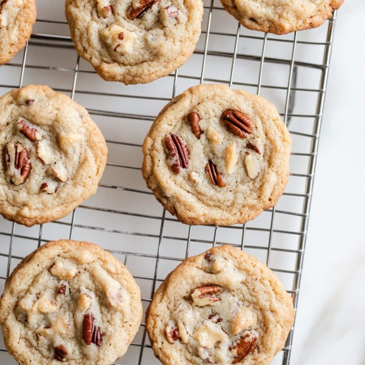 Freshly baked brown butter pecan cookies cooling on wire rack
