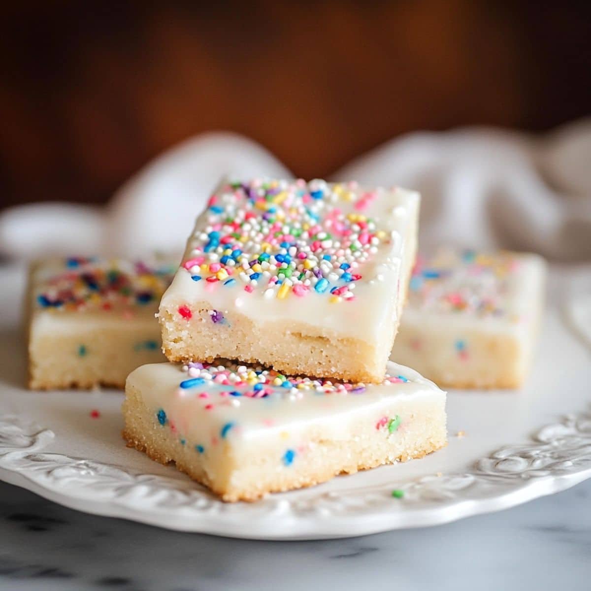 Frosted bar sugar cookie with sprinkles and bite taken	
