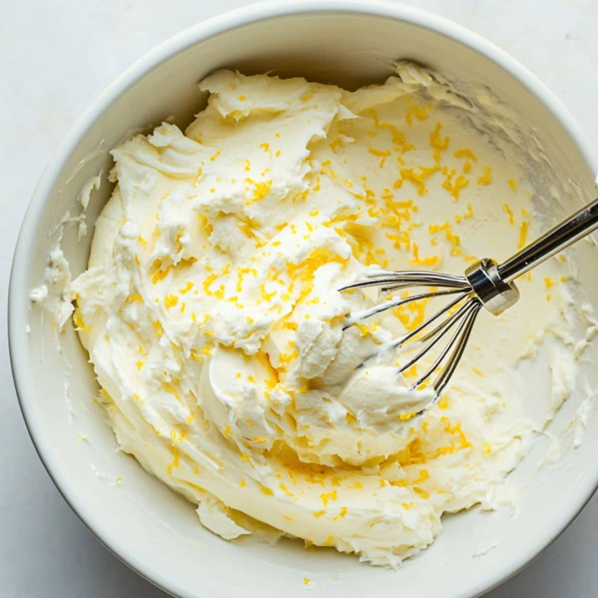 Checking the smooth, spreadable consistency of lemon cream cheese frosting.	
