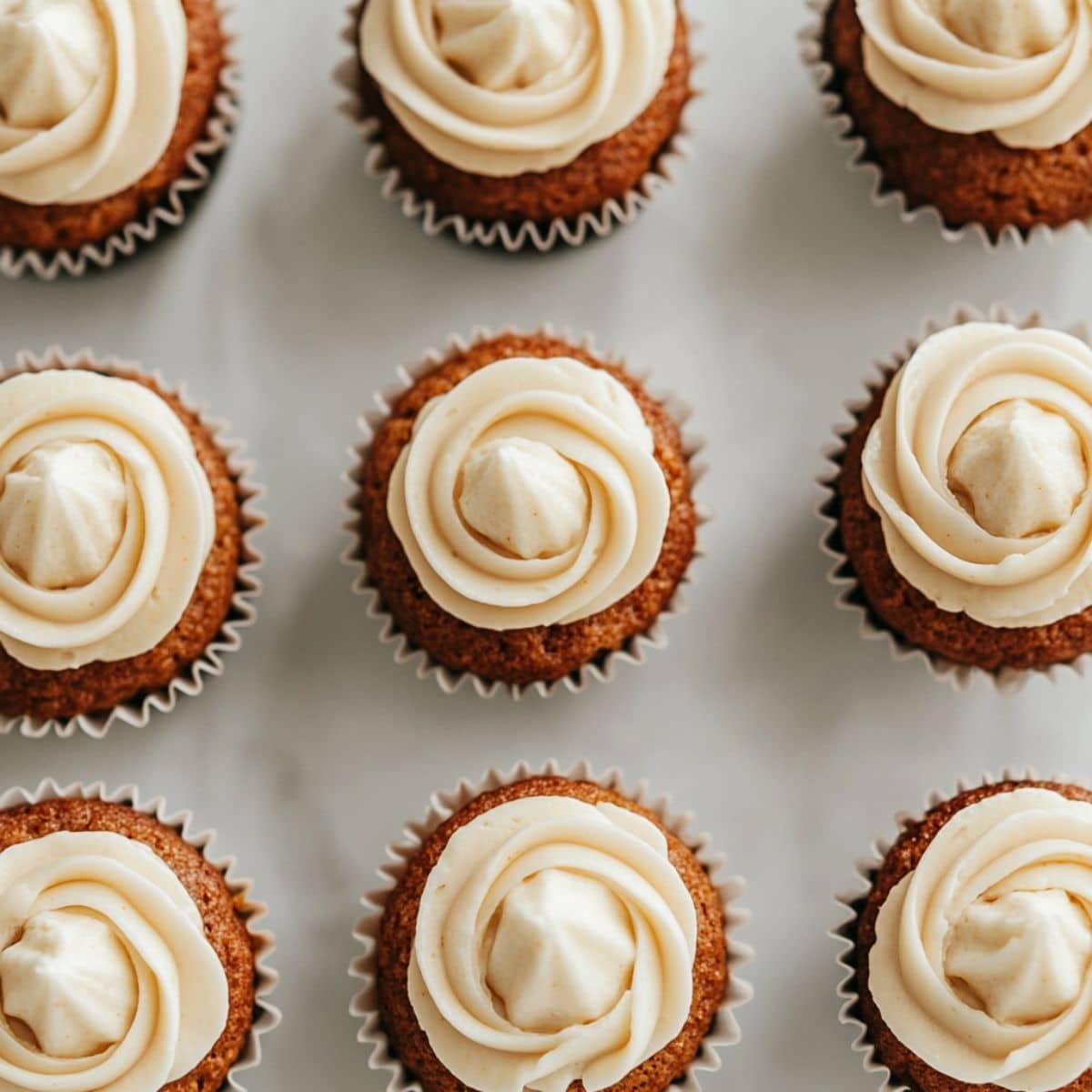 Frosting mini carrot cupcakes with cream cheese icing	