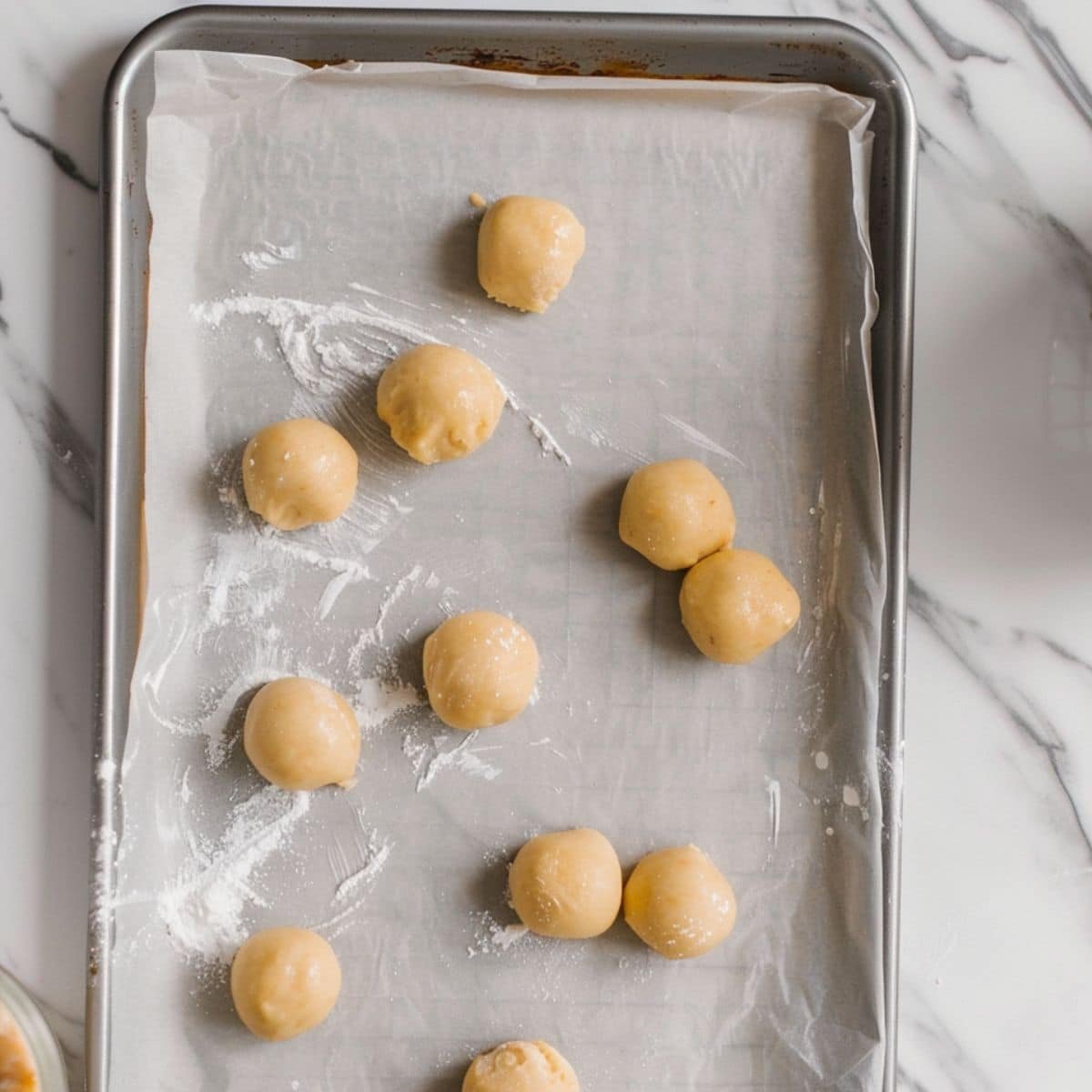 Dough balls being flattened on a baking sheet	