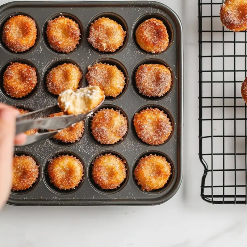 Freshly baked churro cheesecake bites cooling in a muffin tin	