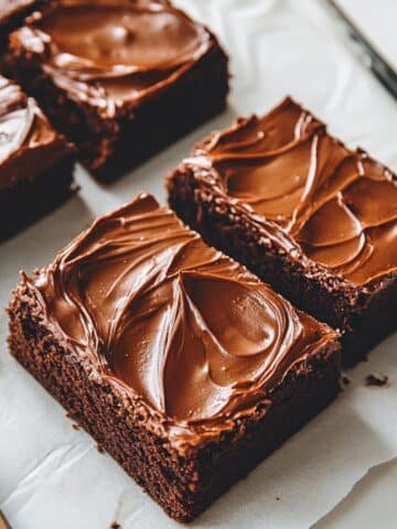Fudgy homemade Lunch Lady Brownies with chocolate frosting on a white kitchen counter.