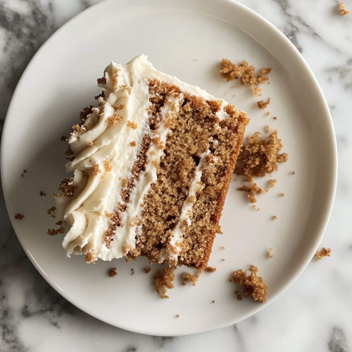 A slice of moist spice cake with cream cheese frosting on a plate. Homemade, cozy feel with visible spice crumbs.