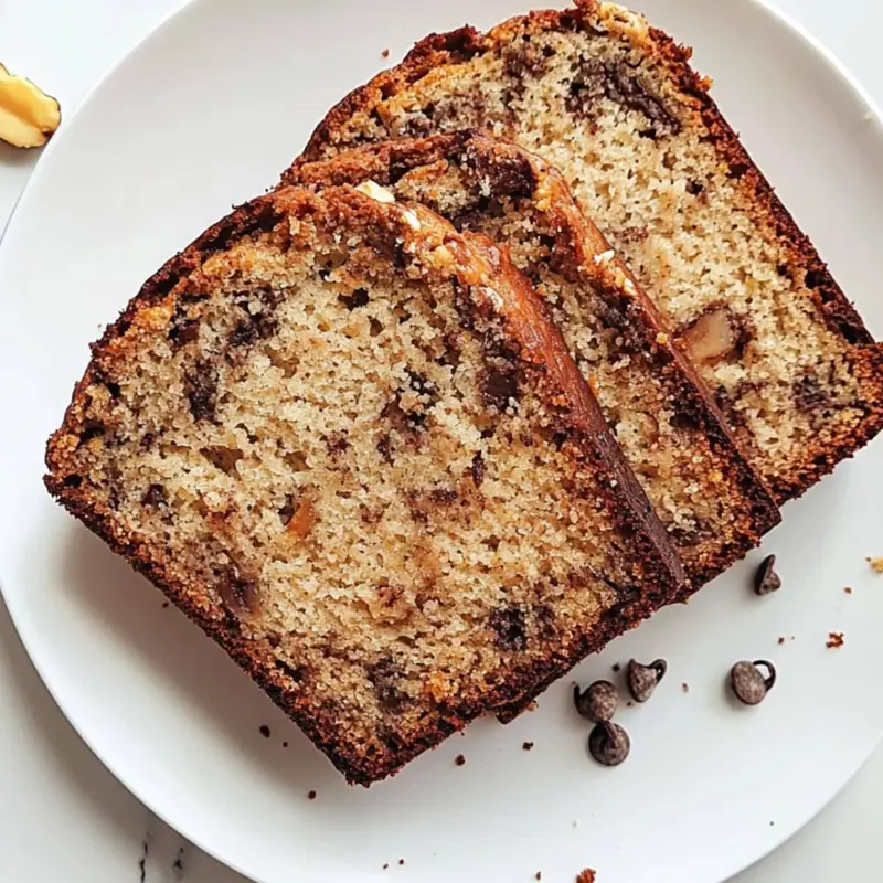 Stack of moist Banana Greek Yogurt Bread slices with chocolate chips and walnuts on a white counter	