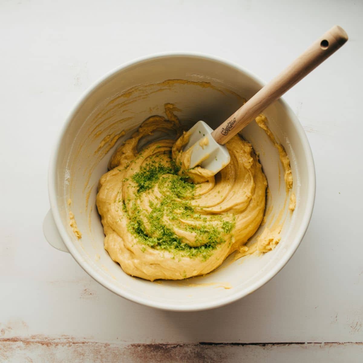 Creamed cookie dough with lime zest and vanilla being mixed in bowl	