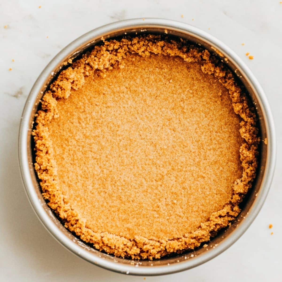 Pressing graham cracker crust into a springform pan 