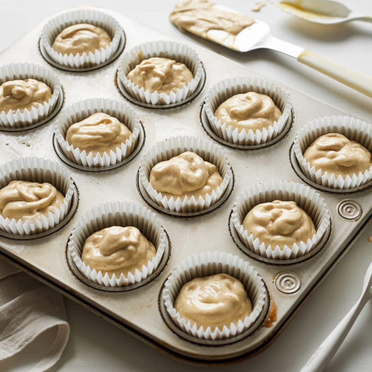 Homemade tiramisu cupcake batter in white paper liners before baking	