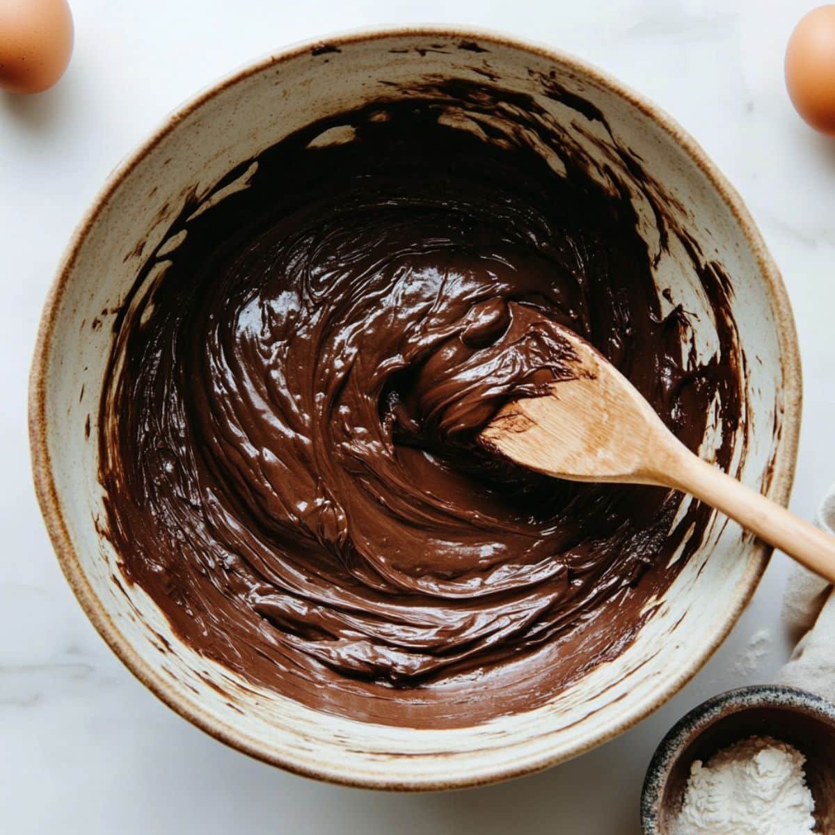 Chocolate cake batter being mixed next to a bundt pan	
