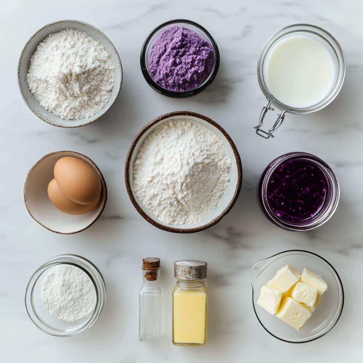 All ingredients for homemade ube cake laid out on white counter. Includes purple yam, flour, milk, and more.