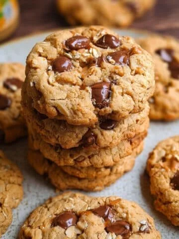 A batch of homemade chocolate chip oatmeal peanut butter cookies with gooey centers on a white kitchen counter