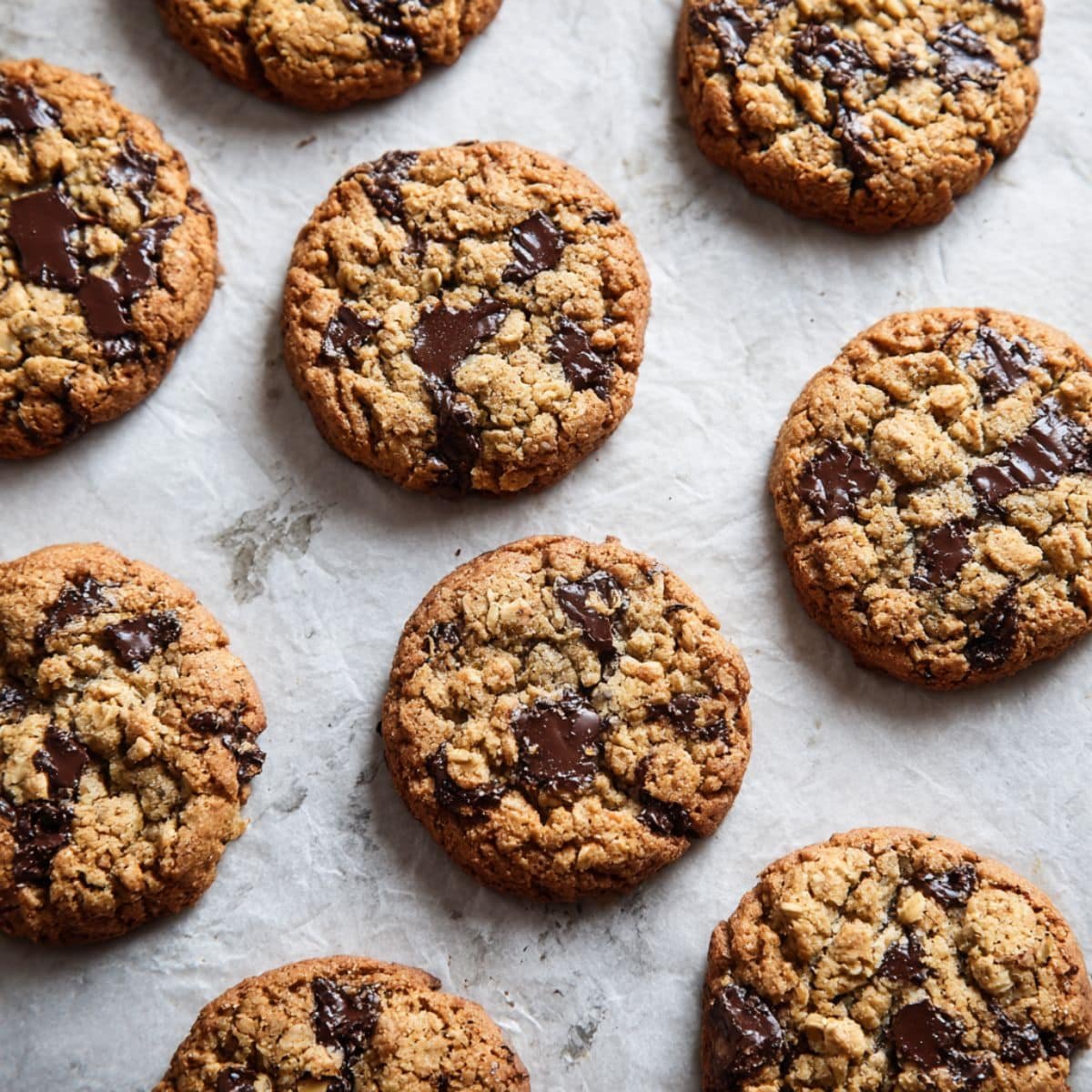 Freshly baked oatmeal peanut butter cookies on parchment-lined tray cooling on counter	