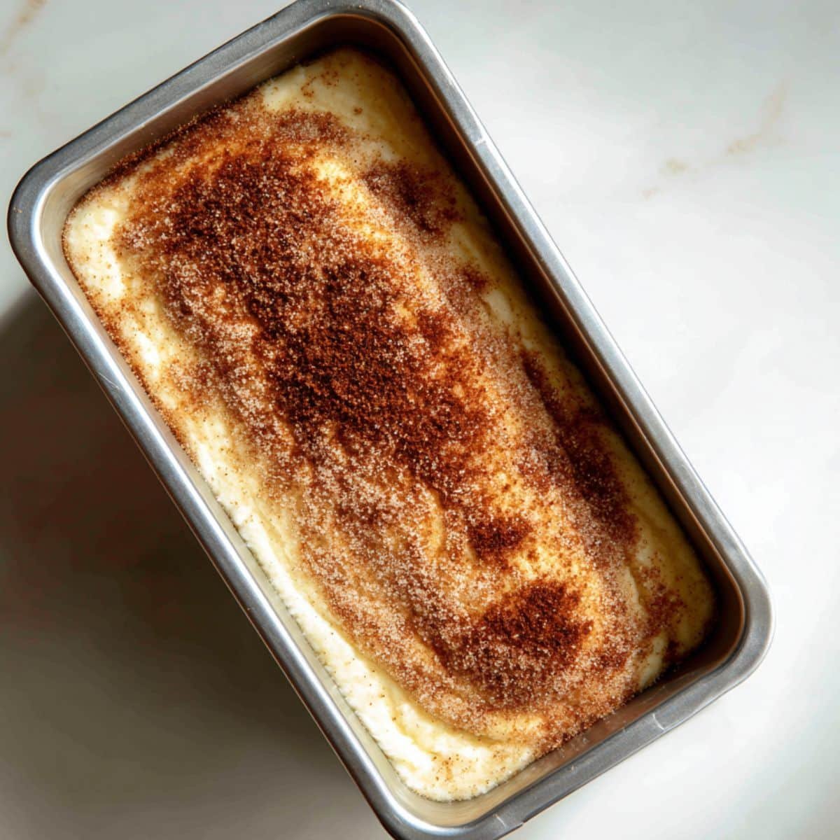 First layer of batter covered with cinnamon sugar in loaf pan