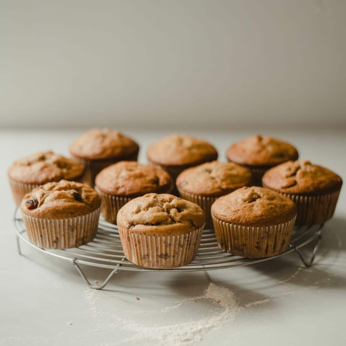 Freshly baked raisin bran muffins cooling on a wire rack.	