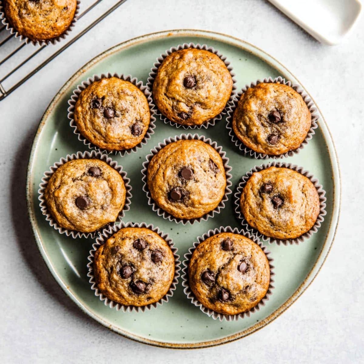 Top-down view of freshly baked banana protein muffins cooling on a white kitchen counter	