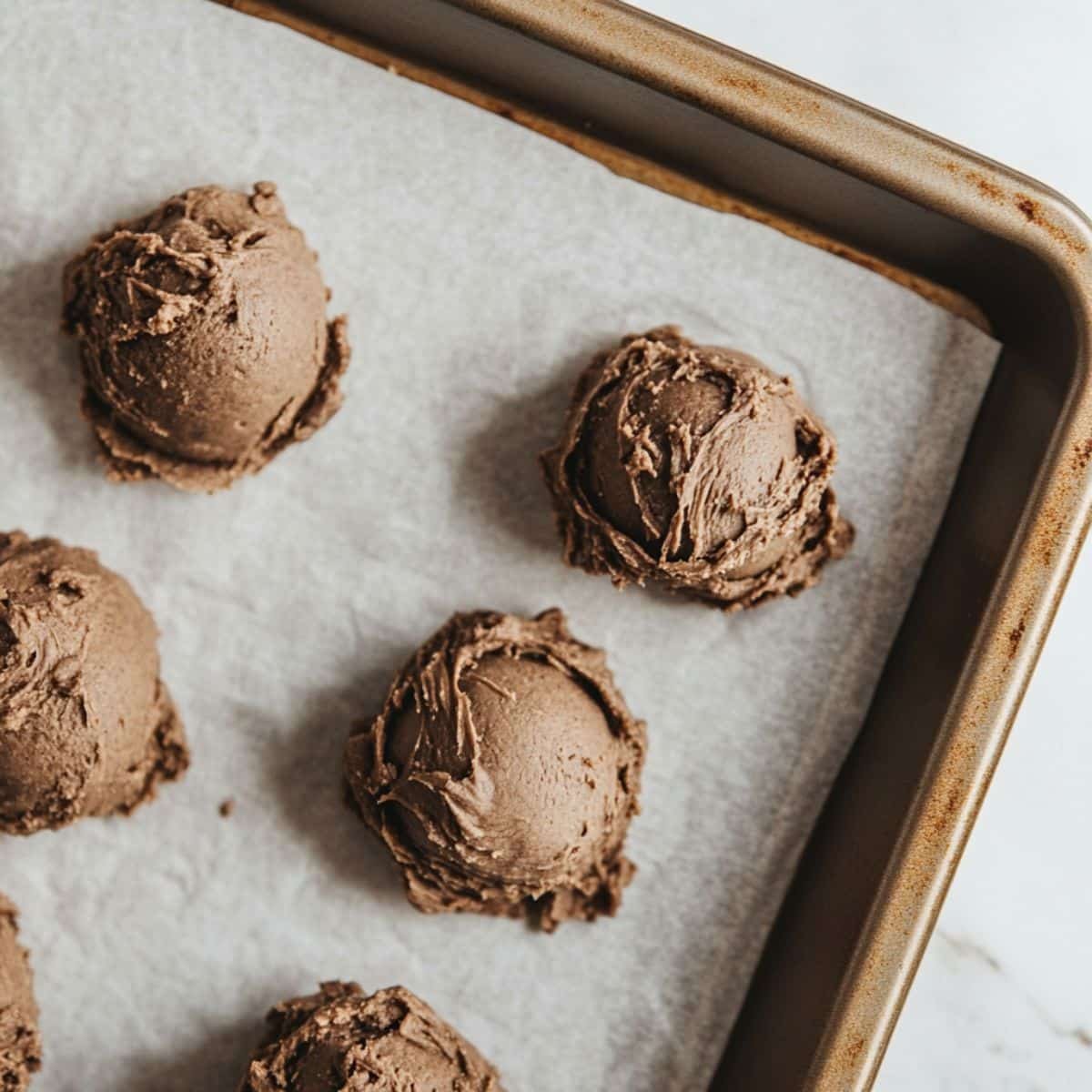 Scooped cookie dough on a parchment-lined baking sheet	