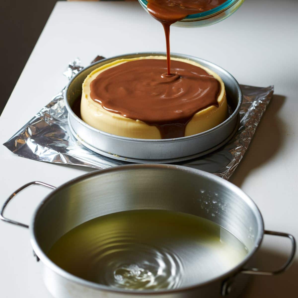 Flan and chocolate batters layered in a bundt pan, roasting pan with water bath prepared	