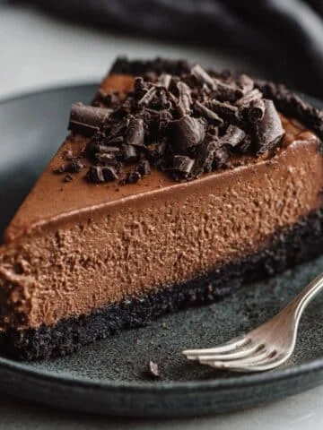 Slice of rich chocolate cheesecake with Oreo crust and chocolate shavings
