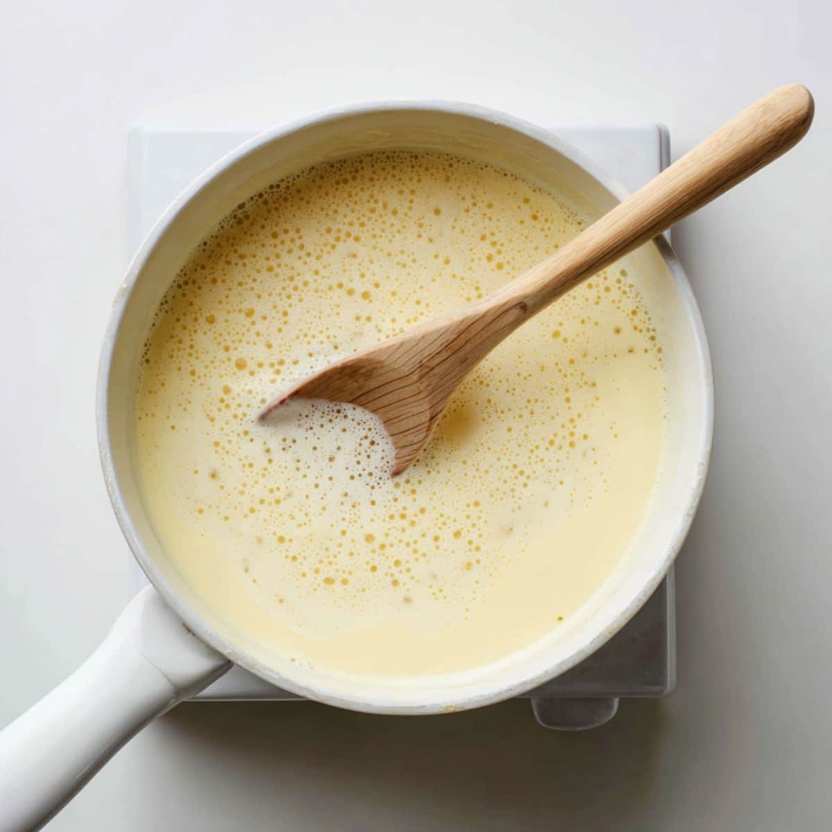 Pastry cream cooking in a saucepan with whisk, thickening on stove	