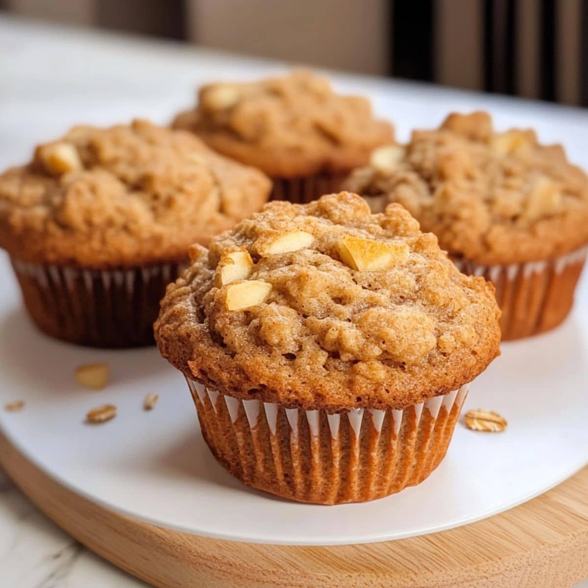 Homemade apple cinnamon oatmeal muffins on a white plate with one broken open	
