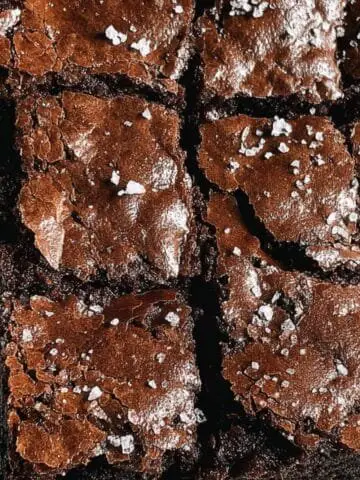 Fudgy homemade flourless brownies stacked on a plate, top-down view
