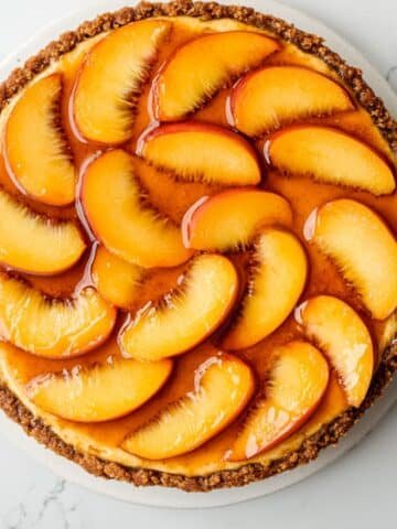 Homemade peach cheesecake recipe topped with fresh glazed peach slices