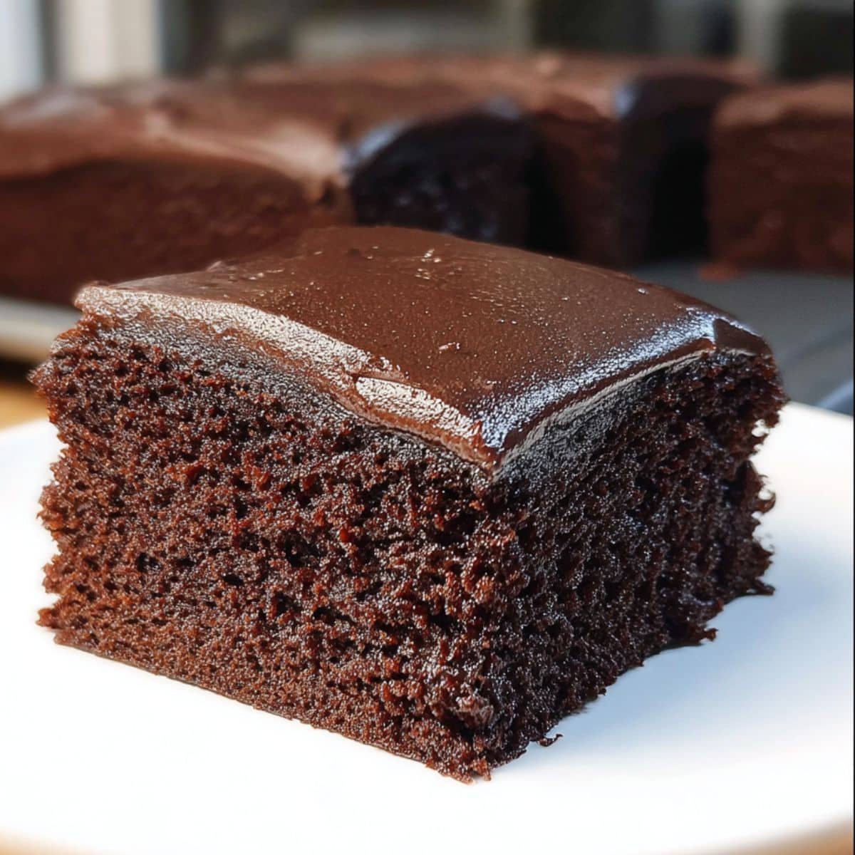 Homemade chocolate sheet cake slices with thick chocolate frosting on white counter	