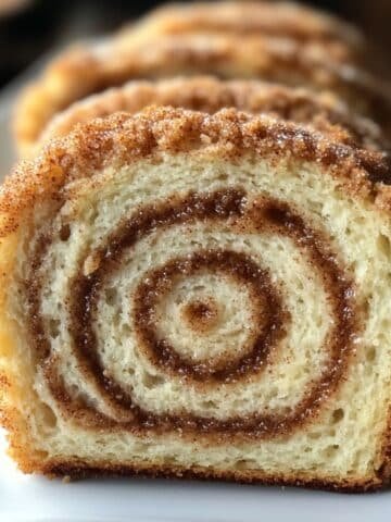 Sliced cinnamon swirl sourdough bread held up to show detailed crumb and spiral pattern.