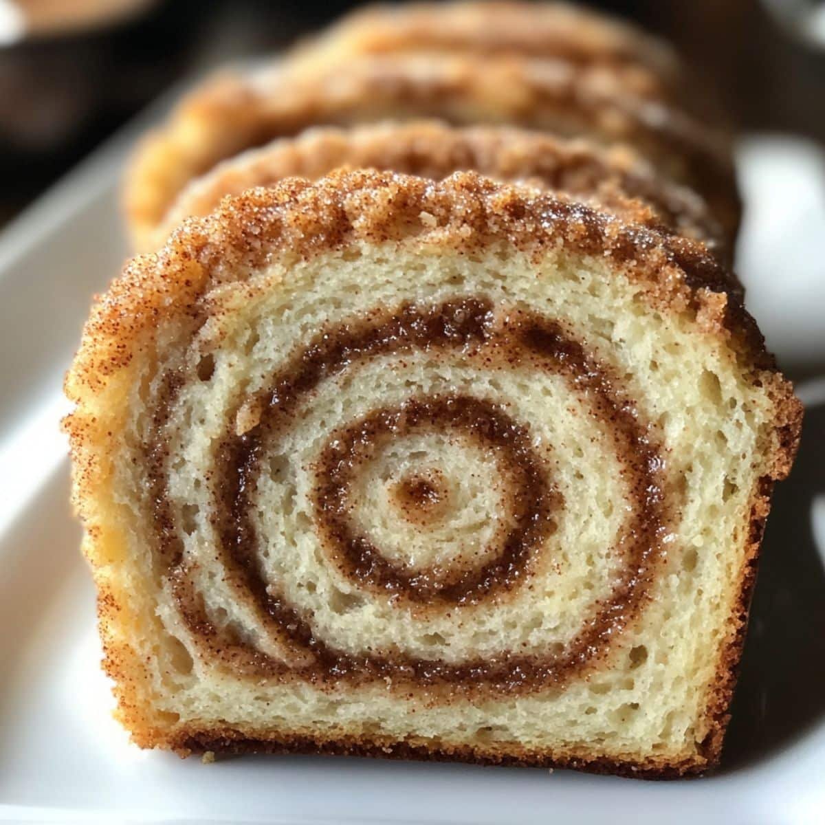 Sliced cinnamon swirl sourdough bread held up to show detailed crumb and spiral pattern.	