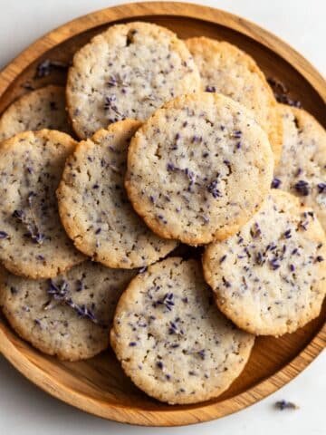 Homemade lavender cookies on wood plate with rustic texture and edible flower garnish