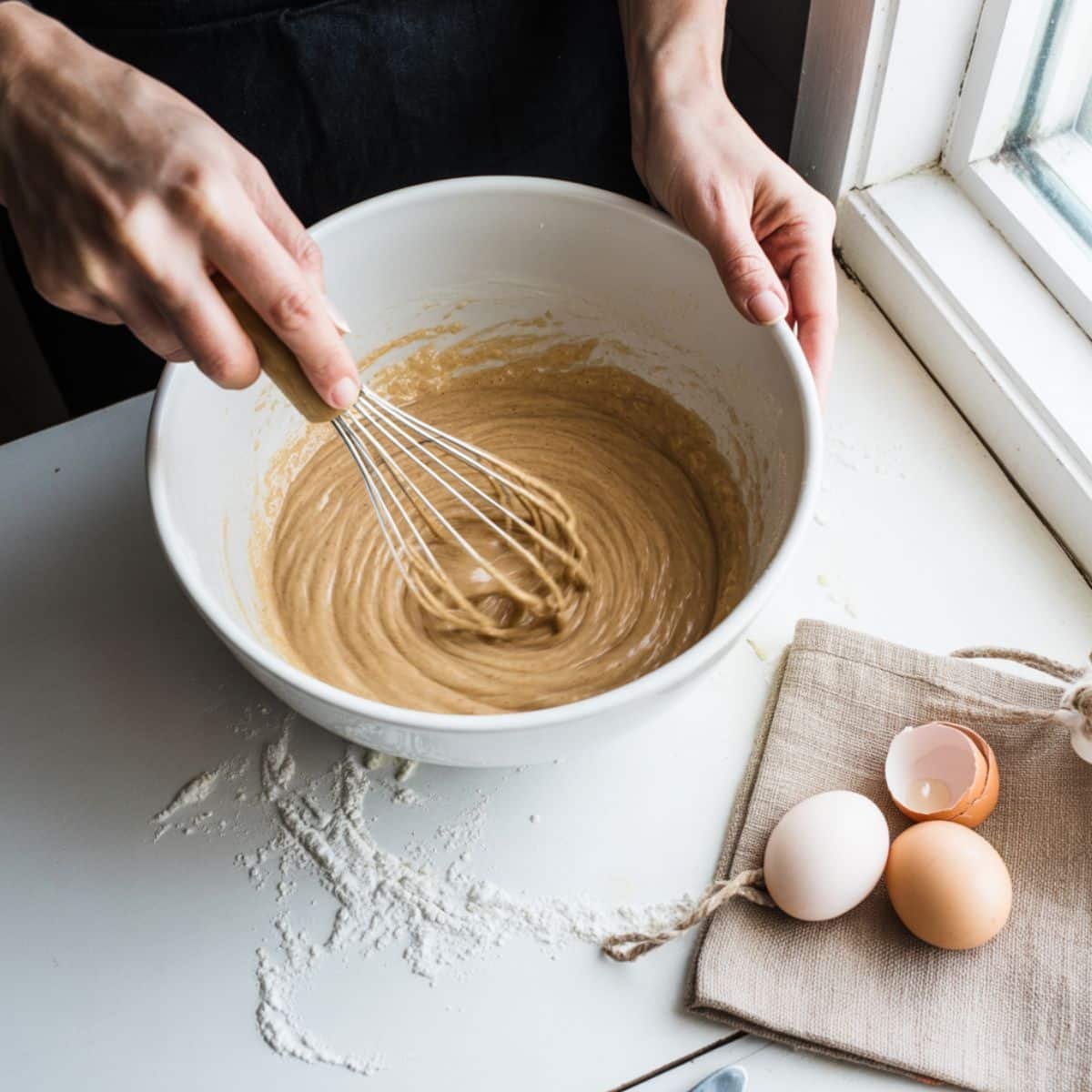 Mixing pancake batter in a large white bowl with a whisk	
