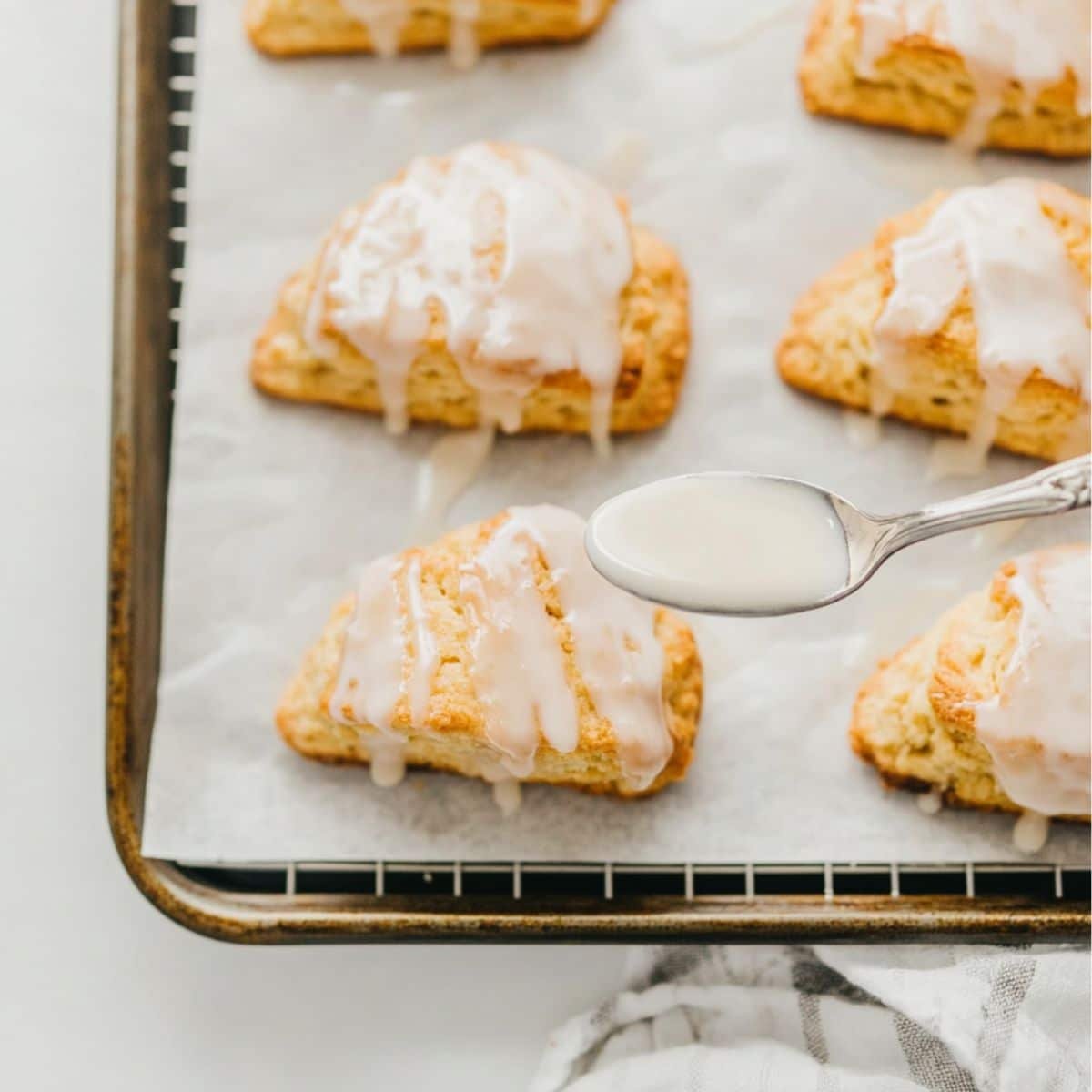 Glazing freshly baked orange scones on baking rack	