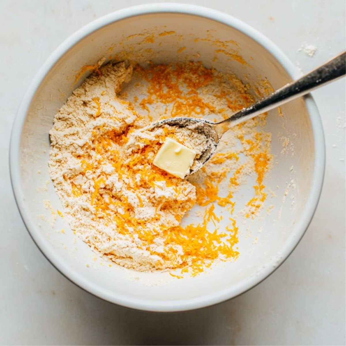 Mixing orange scone dough in white bowl	
