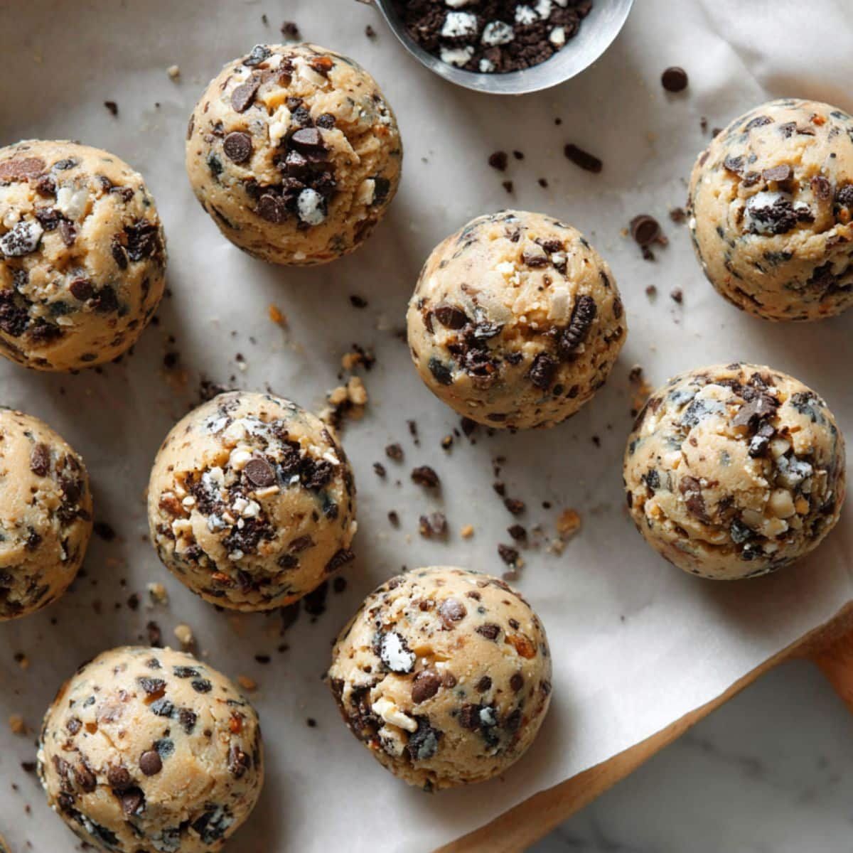 Cookie dough balls with Oreo chunks on a baking sheet	