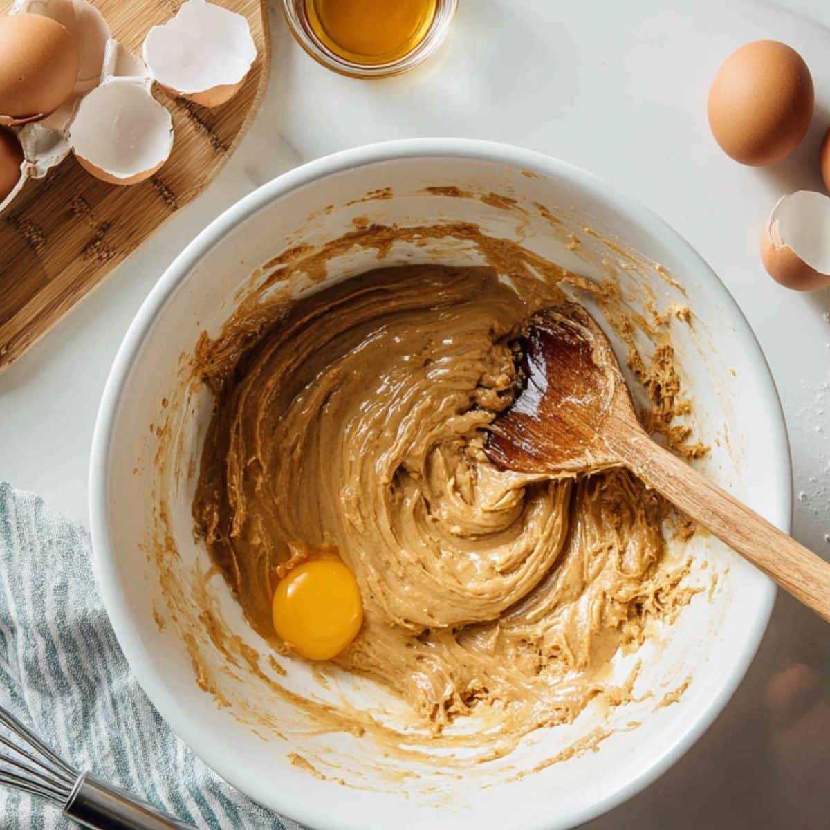 Mixing wet ingredients in a bowl for flourless cookies on white kitchen counter	