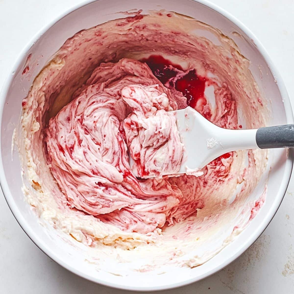 Mixing cookie dough with strawberry jam in a bowl	