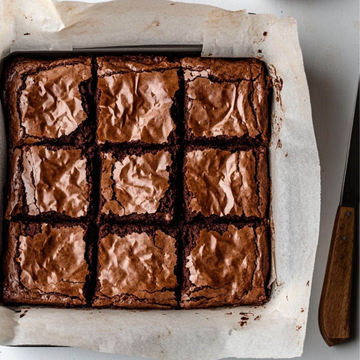 Freshly baked avocado brownies in parchment-lined square pan	