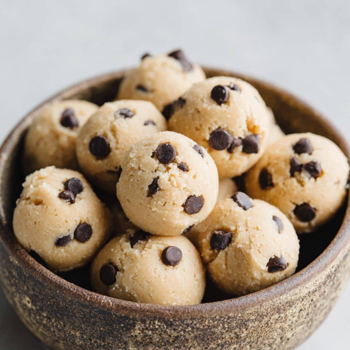 Homemade almond flour cookie dough balls in rustic bowl on white kitchen counter