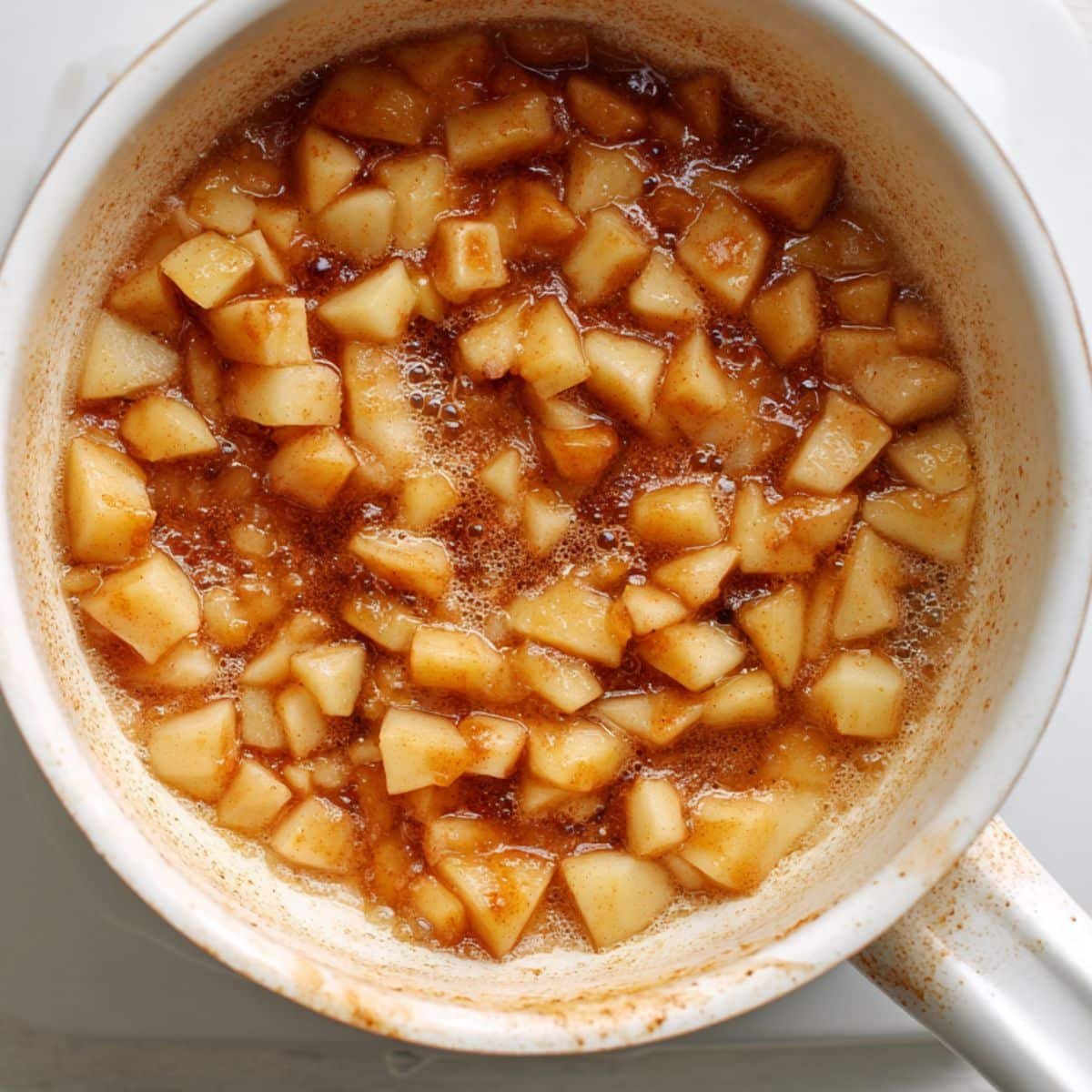 Diced apples cooking in cinnamon sugar on stove	