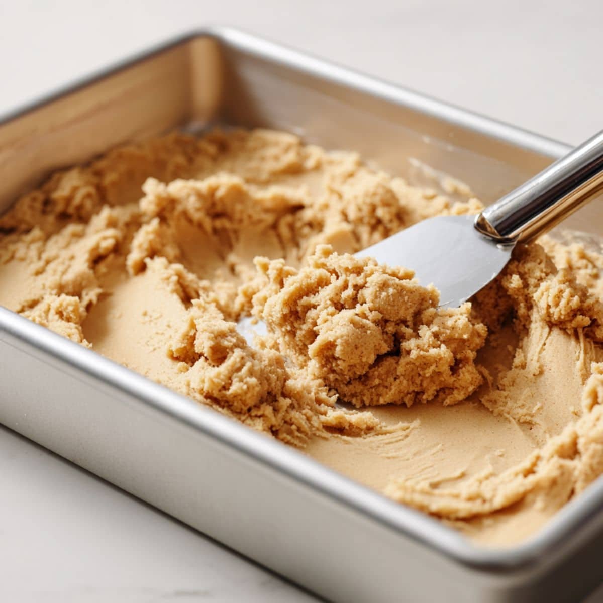 Pressing cinnamon cookie dough into pan for base	