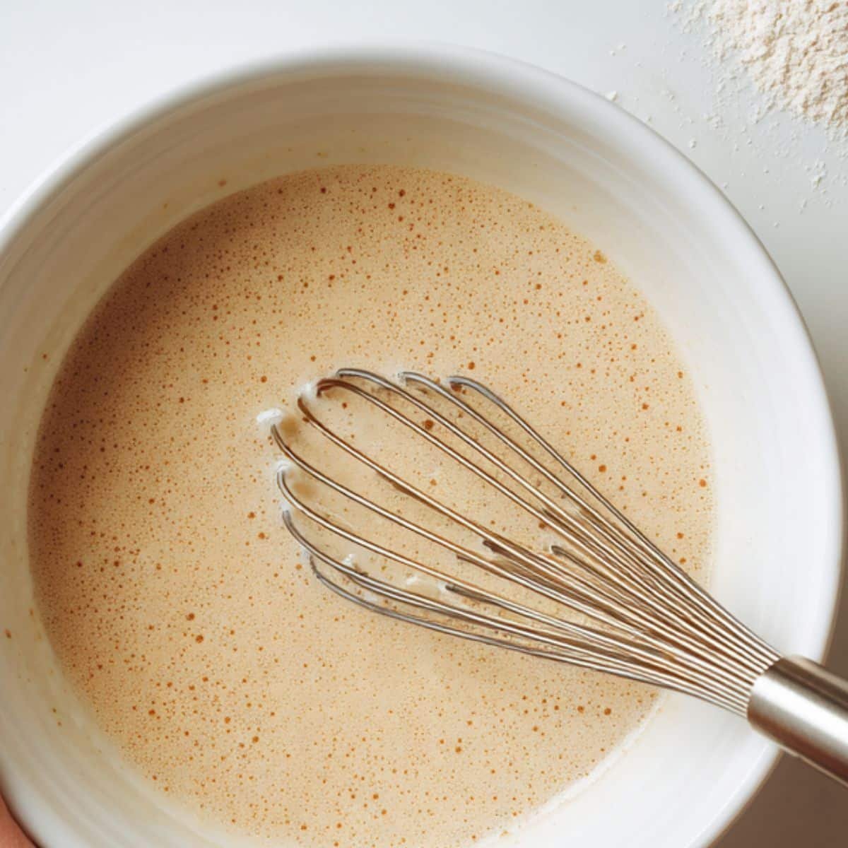 Whisking oat flour pancake batter in a white bowl on kitchen counter	