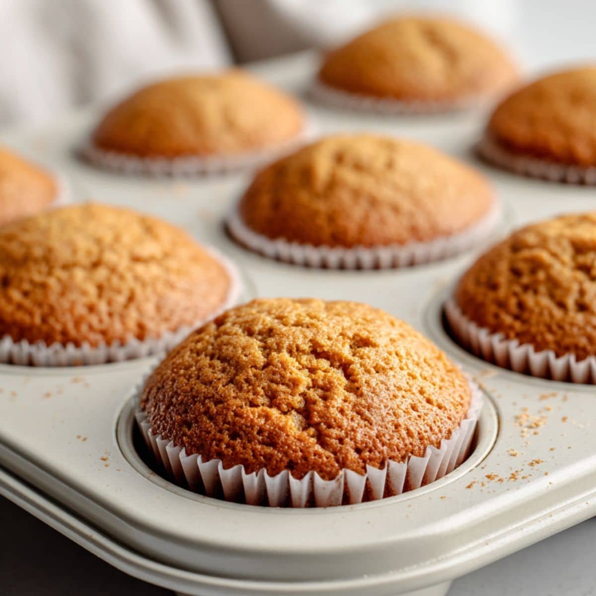 Biscoff cupcakes baking in a muffin tin inside oven	