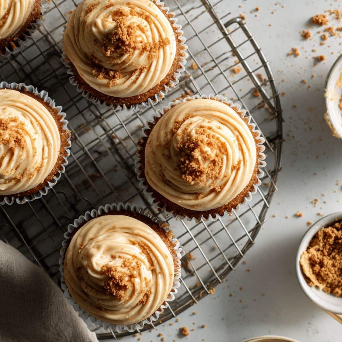 Cupcakes being decorated with Biscoff frosting and crushed cookies	