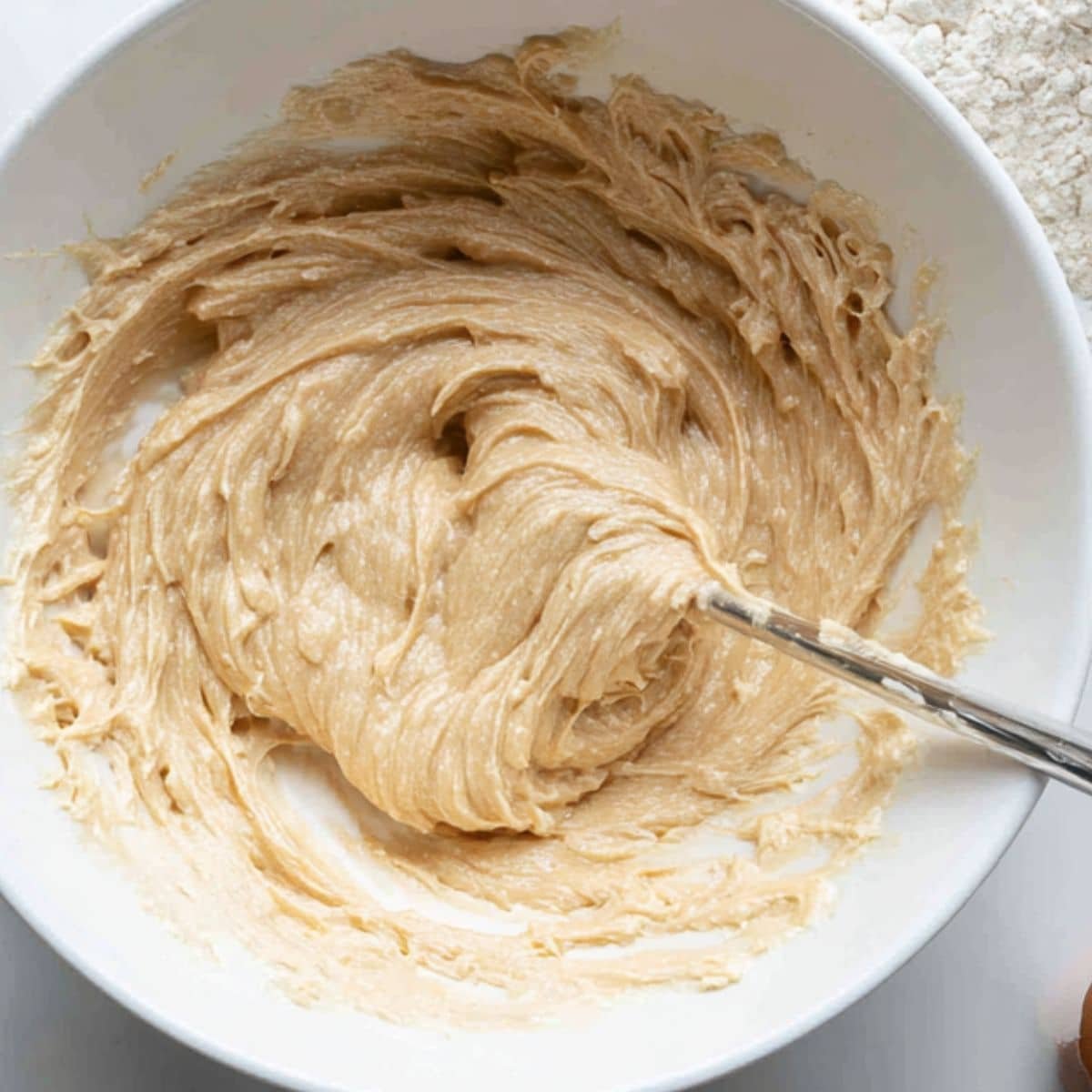 Mixing cupcake batter with Biscoff spread in a white bowl	