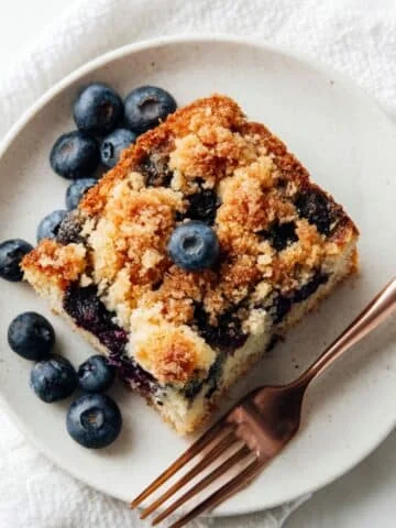 A slice of homemade blueberry sour cream coffee cake on a white plate