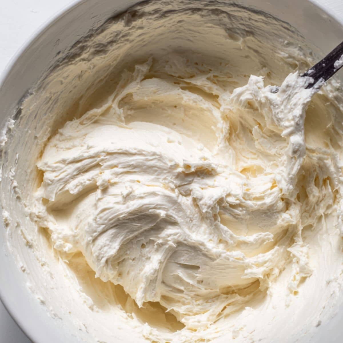 Cream cheese and whipped cream mixture being folded in a mixing bowl	