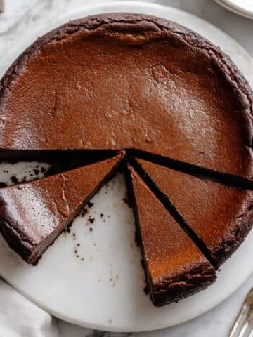 Overhead shot of Chocolate Basque Cheesecake with burnt top and a slice removed on a white counter